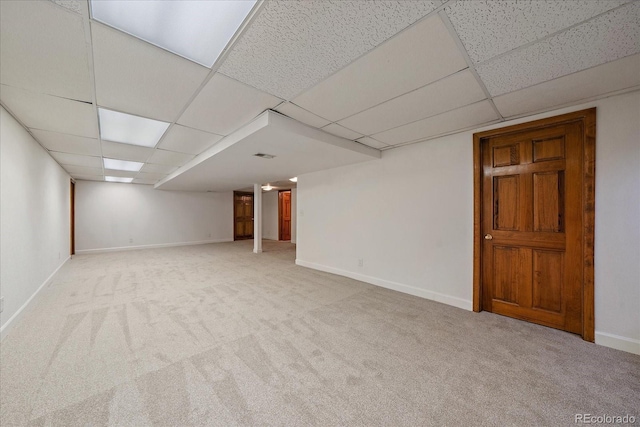 finished basement featuring a drop ceiling, carpet floors, and baseboards