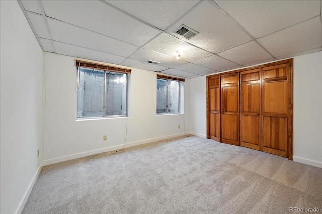 unfurnished bedroom featuring carpet floors, baseboards, and a paneled ceiling