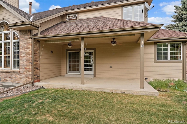 rear view of property featuring ceiling fan, a patio area, a lawn, brick siding, and roof with shingles