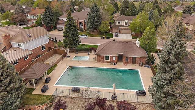 community pool with fence, a residential view, and a patio area