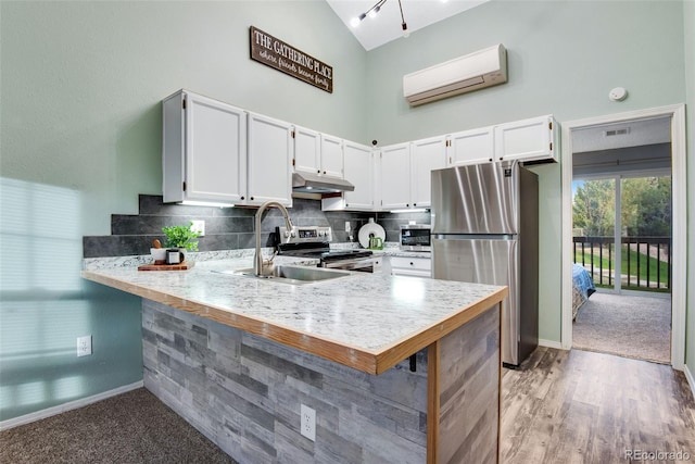 kitchen with white cabinetry, backsplash, a wall mounted AC, kitchen peninsula, and appliances with stainless steel finishes