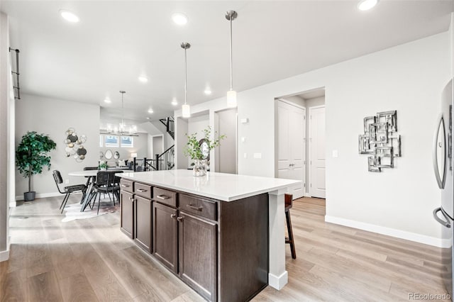 9700 E 63rd Pl, Denver, CO 80238 - kitchen with dark brown cabinetry, baseboards, light wood finished floors, a kitchen bar, and light countertops