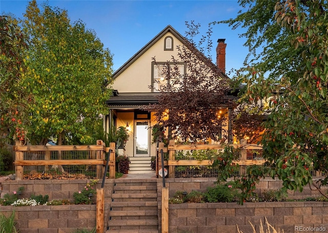 view of front of property featuring a chimney, fence, and stucco siding