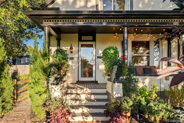 entrance to property with a porch and fence