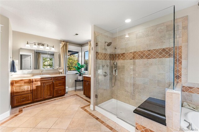 bathroom featuring a tile shower, vanity, and baseboards