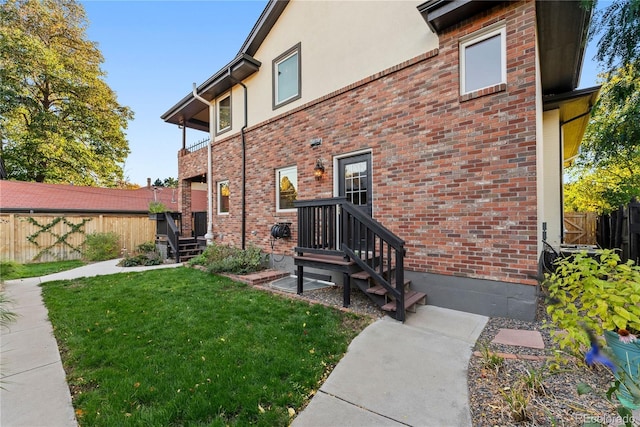 exterior space with a yard, brick siding, fence, and stucco siding