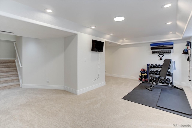 workout room featuring light colored carpet and a raised ceiling