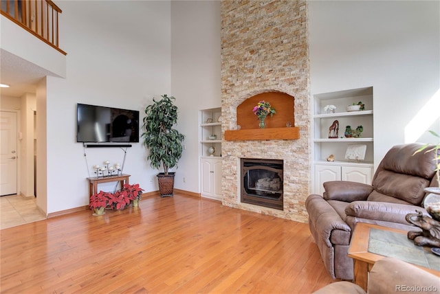 living room featuring a towering ceiling, built in features, and light wood-type flooring