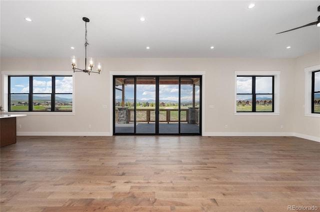 interior space with ceiling fan with notable chandelier, light hardwood / wood-style flooring, and a wealth of natural light