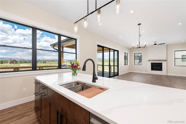 kitchen featuring pendant lighting, a fireplace, sink, a chandelier, and dark wood-type flooring