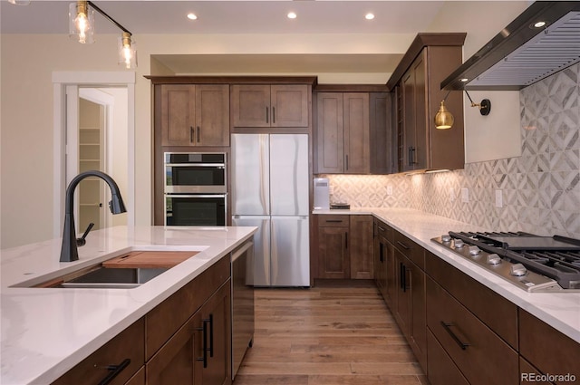 kitchen featuring premium range hood, appliances with stainless steel finishes, sink, and pendant lighting