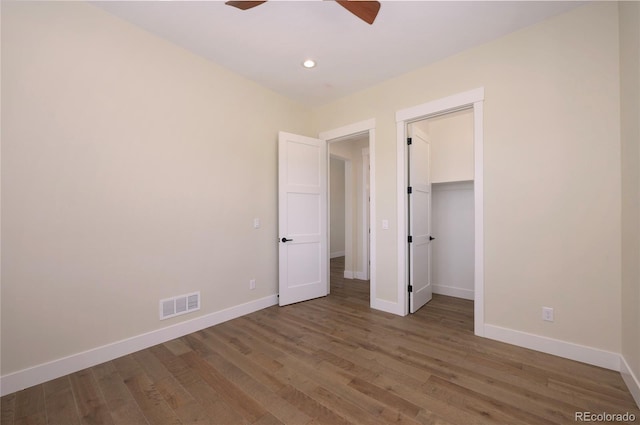 unfurnished bedroom with dark wood-type flooring, ceiling fan, and a walk in closet