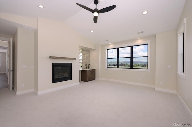 unfurnished living room with lofted ceiling, sink, light colored carpet, and ceiling fan