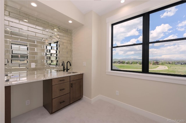 bar with light stone countertops, dark brown cabinets, sink, and light carpet