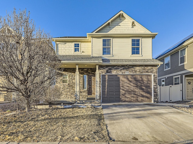 view of front facade featuring concrete driveway, stone siding, roof with shingles, an attached garage, and fence