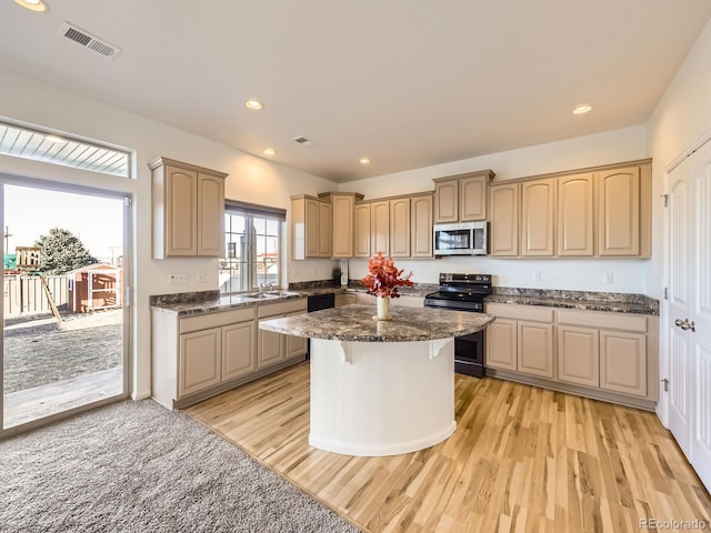 kitchen featuring a sink, visible vents, a center island, electric range oven, and stainless steel microwave