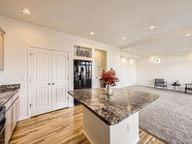 kitchen featuring light wood finished floors, black fridge, a kitchen island, and recessed lighting