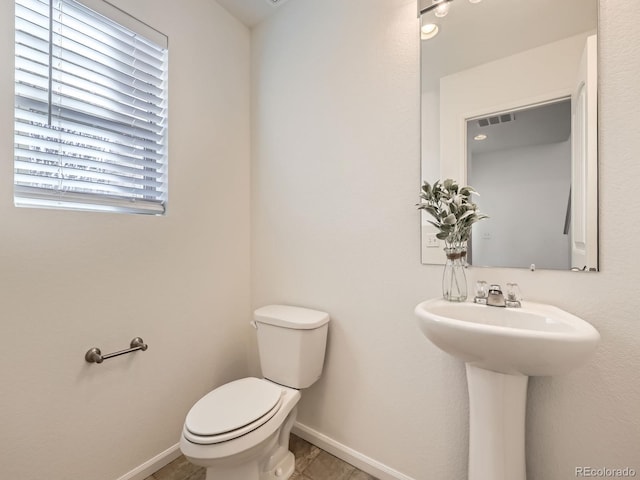 half bathroom with toilet, visible vents, and baseboards