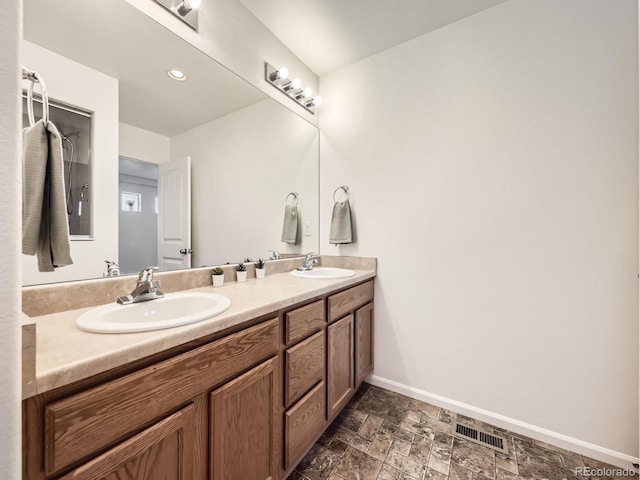 bathroom with double vanity, baseboards, visible vents, and a sink