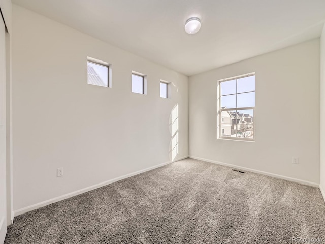 spare room with carpet, visible vents, and baseboards