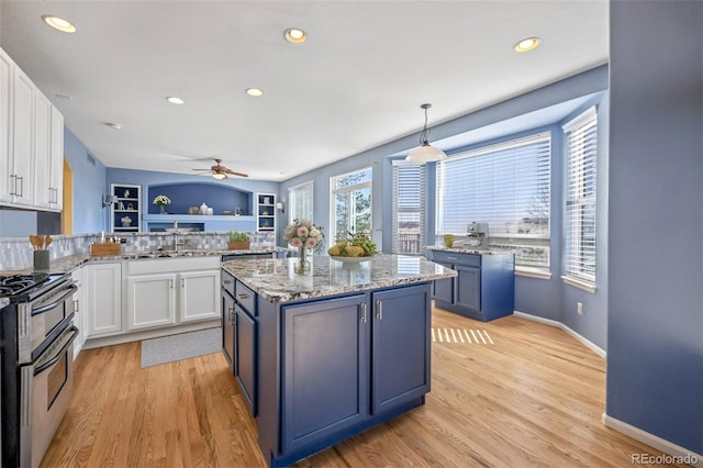 1929 Baguette Dr, Castle Rock, CO 80108 - kitchen with range with two ovens, white cabinets, ceiling fan, light wood finished floors, and recessed lighting