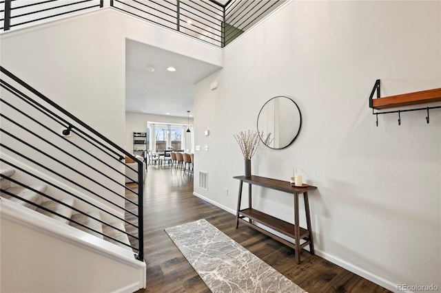 foyer entrance featuring dark wood-style floors, visible vents, stairway, and baseboards