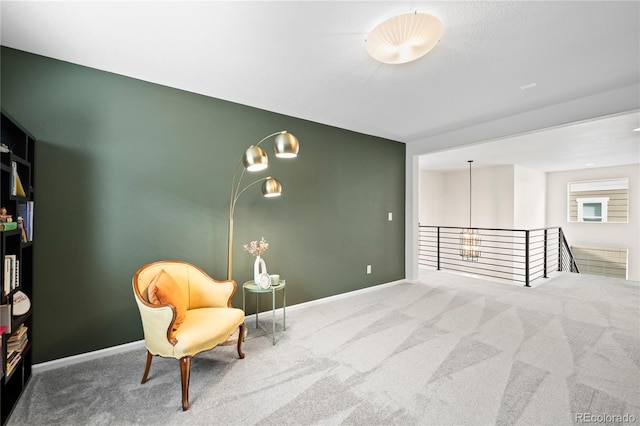 sitting room with carpet floors, an upstairs landing, and baseboards