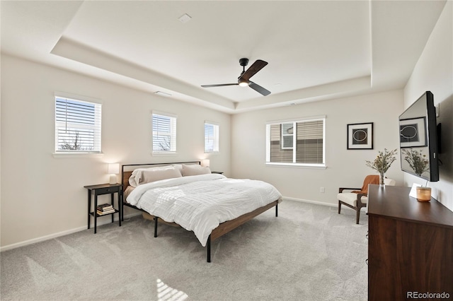 bedroom featuring a tray ceiling, light colored carpet, and baseboards