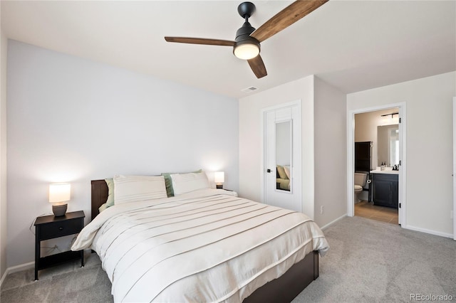 bedroom featuring ceiling fan, ensuite bathroom, light carpet, visible vents, and baseboards