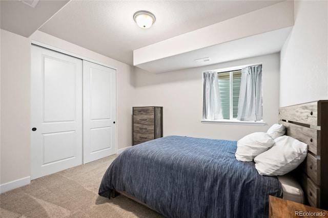 bedroom featuring baseboards, a closet, and light colored carpet