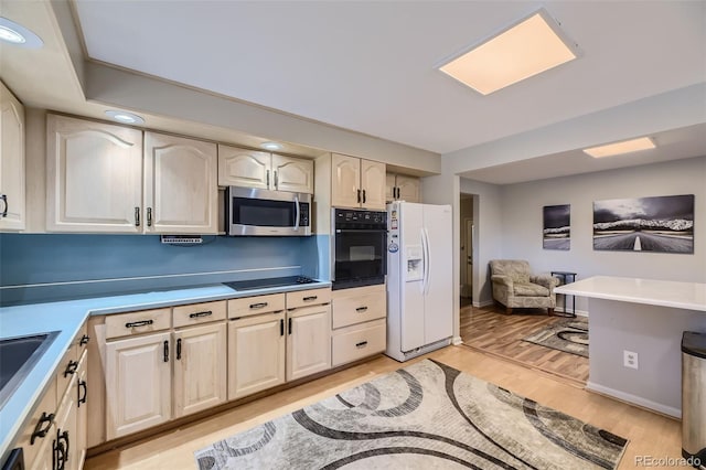 kitchen featuring light wood-type flooring, white fridge with ice dispenser, cooktop, and oven