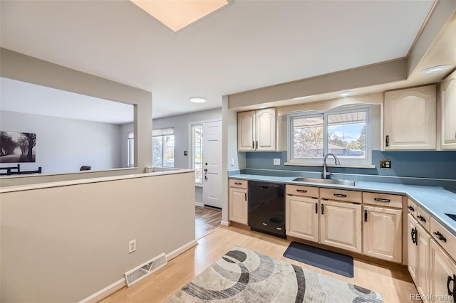 kitchen with black dishwasher, light wood-type flooring, sink, and light brown cabinetry