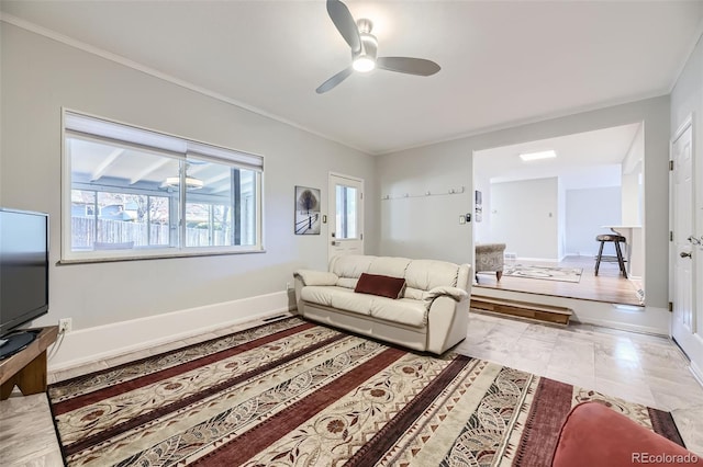 tiled living room with ceiling fan and crown molding