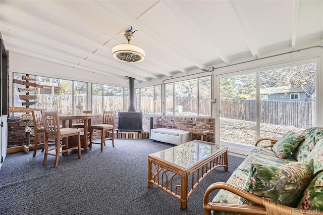 sunroom / solarium featuring a wood stove and vaulted ceiling with beams