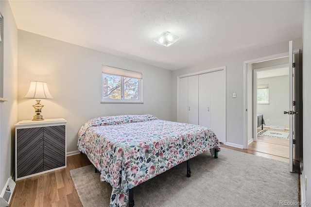 bedroom with a closet, multiple windows, hardwood / wood-style floors, and a textured ceiling