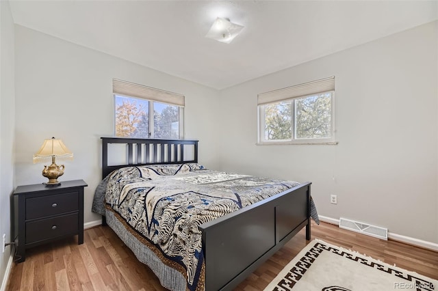 bedroom with wood-type flooring and multiple windows