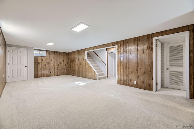 basement featuring light colored carpet and wooden walls