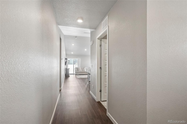 hallway with dark hardwood / wood-style flooring and a textured ceiling