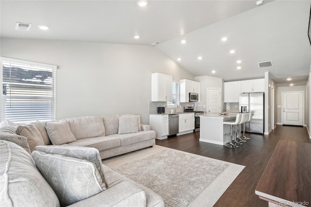 living room featuring sink, dark wood-type flooring, a wealth of natural light, and vaulted ceiling