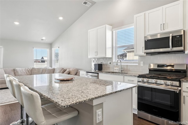 kitchen featuring sink, white cabinetry, stainless steel appliances, a kitchen breakfast bar, and a kitchen island