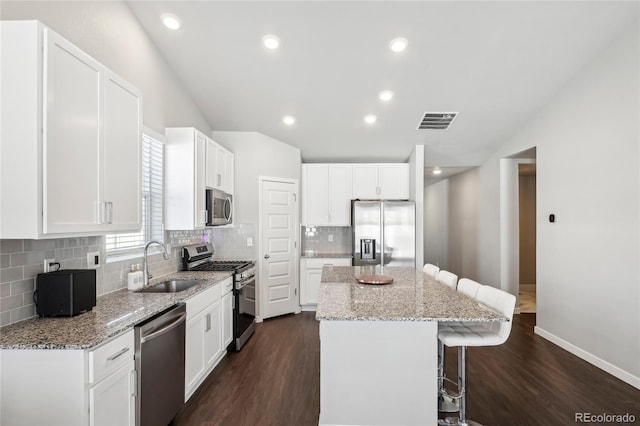 kitchen featuring white cabinetry, appliances with stainless steel finishes, light stone counters, and a kitchen island