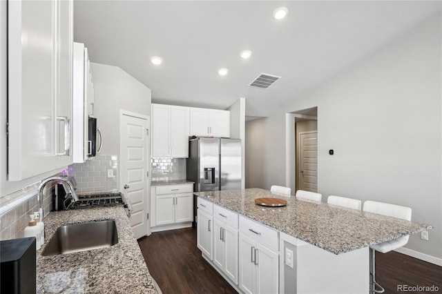 kitchen with a kitchen breakfast bar, a center island, white cabinets, and appliances with stainless steel finishes