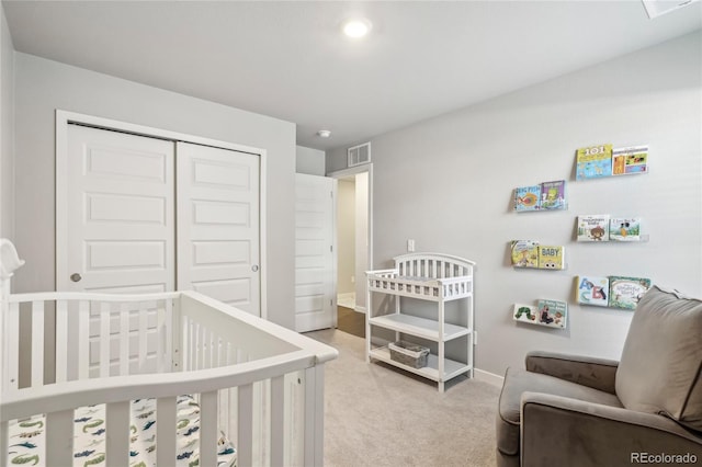 bedroom featuring a nursery area, light colored carpet, and a closet