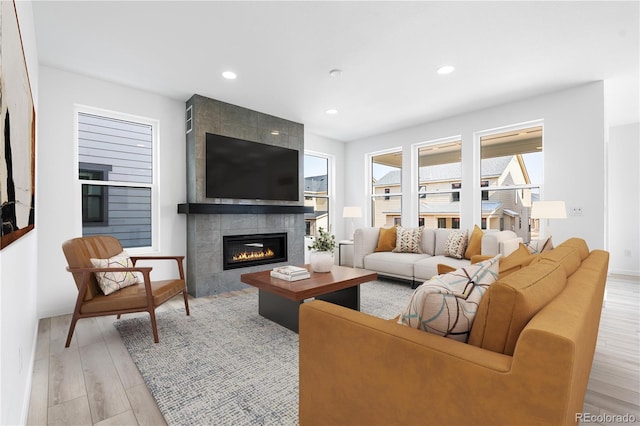 living room featuring light wood-type flooring, recessed lighting, and a tile fireplace