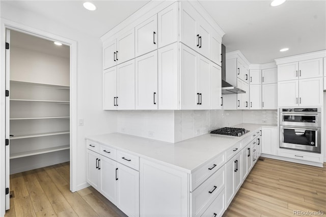 kitchen with stainless steel appliances, light wood finished floors, and white cabinets