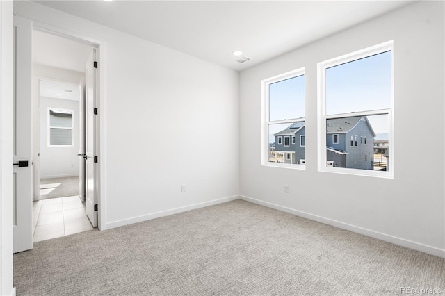 empty room with a healthy amount of sunlight, light carpet, and baseboards