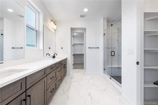 bathroom featuring marble finish floor, a spacious closet, visible vents, and a sink