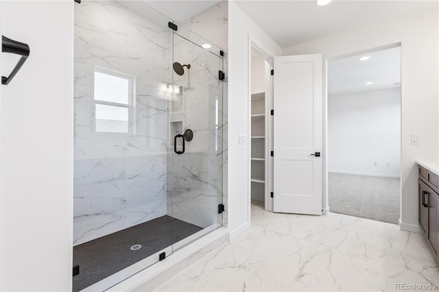 bathroom with recessed lighting, vanity, marble finish floor, a marble finish shower, and a walk in closet