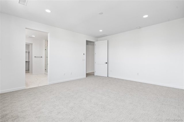 spare room featuring light colored carpet, visible vents, baseboards, and recessed lighting