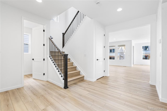 staircase featuring baseboards, wood finished floors, and recessed lighting